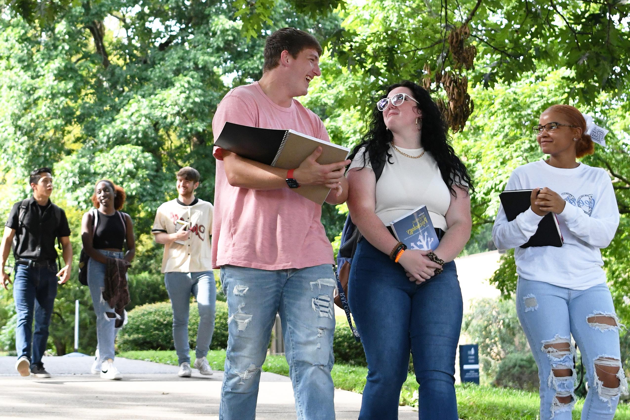 Students walking across campus carrying books.